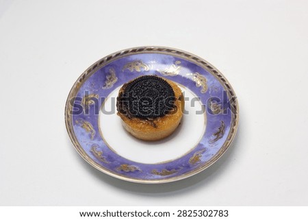 top-down view of a single round cookie-topped cake placed centrally on a blue ceramic saucer with gold patterns.