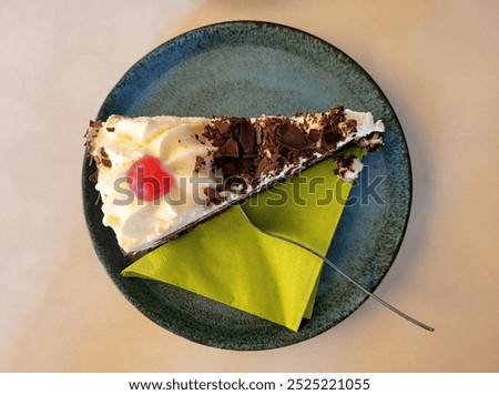 Top-down view of a slice of blackforest cake with a green napkin and a fork