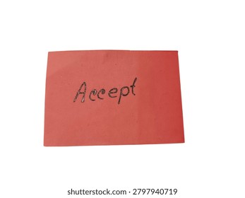 A top-down view of a small rectangular red piece of paper with the word Accept handwritten in dark ink, placed on a textured surface.
