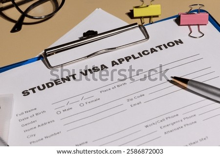 A top-down view of a student visa application form clipped on a clipboard, placed on a desk, symbolizing study abroad processes.