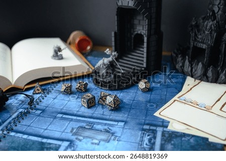 Top-down view of a tabletop RPG setup with dice, miniatures, character sheets, a dice tower, and a fantasy map. Perfect for DnD, strategy games, or role-playing visuals.	
