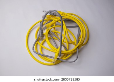 Top-down view of a tangled bundle of yellow and grey Ethernet patch cables, featuring clear RJ45 connectors, isolated against a plain white background.