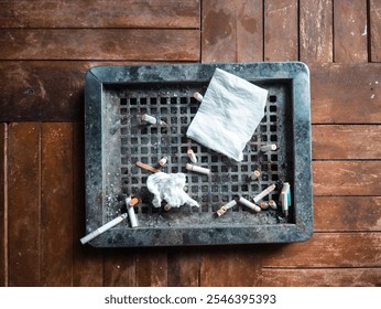 A top-down view of a trash bin upper part put on the wooden table filled with various item, including cigarette butt, tissues and plastic, highlighting waste management issues. World no tobacco day