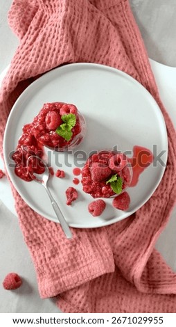 A top-down view of two small jars of creamy chia seed pudding, generously topped with a rich raspberry coulis and fresh raspberries.