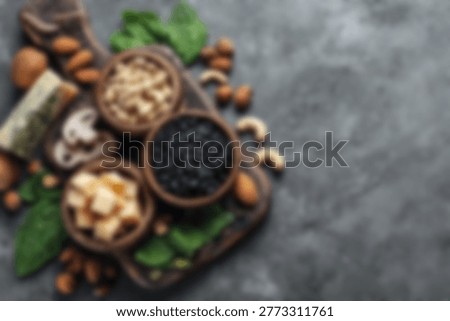 A top-down view of various healthy nuts and seeds arranged in rustic wooden bowls on a dark textured surface, showcasing a variety of textures and colors.