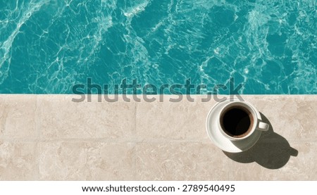 A top-down view of a white cup of coffee placed on the edge of a swimming pool, with clear blue water and sunlight reflecting on the surface.