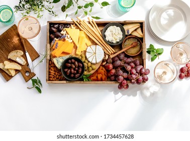 Top-down View Of White Table Surface Set For Light Summer Lunch With A Cheese Platter And Rose Wine, Healthy Food Summer Concept With Blank Space For A Text