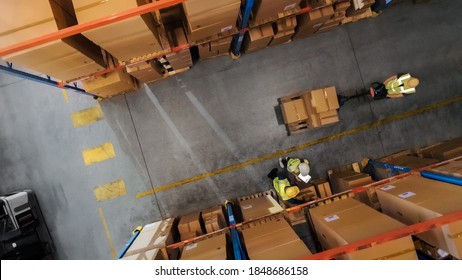 Top-Down View: Worker Moves Cardboard Boxes using Hand Pallet Truck, Walking between Rows of Shelves with Goods in Retail Warehouse. People Work in Product Distribution Logistics Center - Shutterstock ID 1848686158