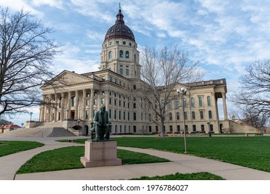 Topeka, KS United States of America - March 27th, 2021: Kansas State Capitol Building, with statue of Abraham Lincoln in foreground.  Wide angle shot of Statehouse grounds with grass and paths.