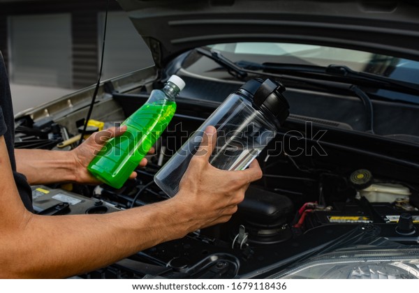 Topic of car repair shop: hands showing choice\
of coolant antifreeze or water for car coolant system. maintenance\
fluids or engine products