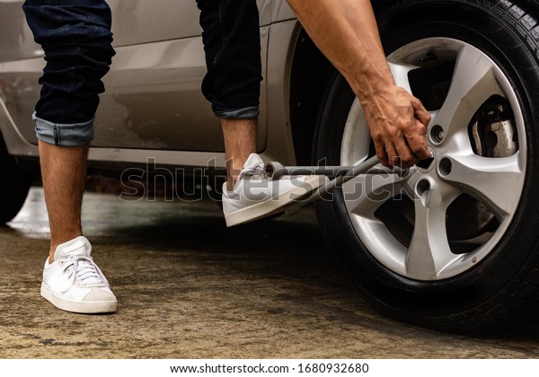 Topic of\
problems with the car on the road. man using force to loosen bolts\
on car tire. roadside assistance\
concept