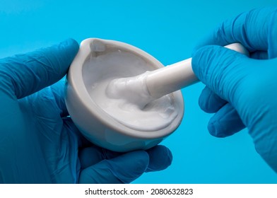 Topical Drugs, Drugstore Laboratory And Pharmaceutical Medication Concept Pharmacist Wearing Gloves Is Mixing A Prescription Lotion With Mortar And Pestle Isolated On Blue Background