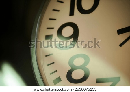 Top-left angle view of an analog clock captured from 9 to 11 o’clock positions, with natural light reflection.