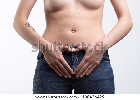 A topless caucasian woman making a love heart sign with her hands over her womb in a maternity themed portrait with copy space.