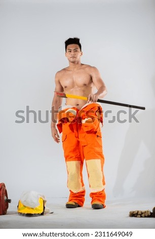 Topless firefighter's holding an iron axe while smile on his face showcases his self assuredness on white background.