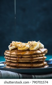 Topping pancakes pile with maple syrup.Healthy brunch
