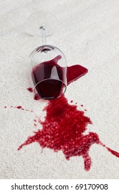 A Toppled Glass Of Red Wine With A Dirty Carpet.