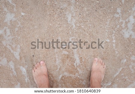 Topview foot with ocean wave bubble on sandy beach. Background for vacation holiday and natural feeling.