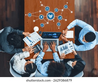 A top-view image of a collaborative business meeting featuring diverse professionals analyzing digital data and charts on laptops, fostering strategy and innovation. Amity