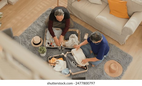 topview old asian senior couple packing cloth and stuff for a trip together,happiness asian old age retired mature adult enjoy arrange cloth together on floor at living room at home interior place - Powered by Shutterstock