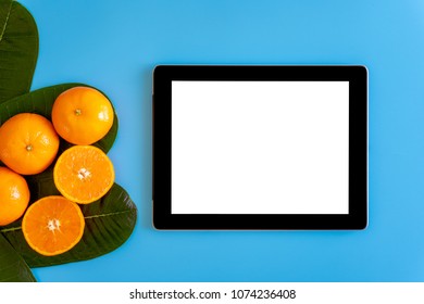 Topview Of Orange With Desktop With Blank White Tablet On Plates Blue Background. Topview Or Flat Lay Fruit.