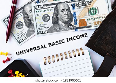 Topview photo on Universal Basic Income theme. The words Universal Basic Income on paper, surrounded by dollar banknotes, notepad, wallet and red pen - Shutterstock ID 1921900601