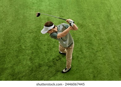 Top-view portrait of male golfer, skilled, focused on game golf player in mid follow-through on artificial grass. Concept of professional sport, luxury games, active lifestyle, action. Ad - Powered by Shutterstock