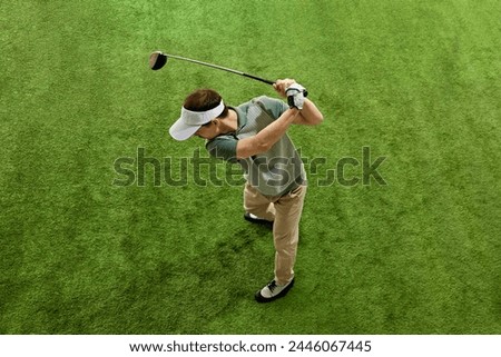 Top-view portrait of male golfer, skilled, focused on game golf player in mid follow-through on artificial grass. Concept of professional sport, luxury games, active lifestyle, action. Ad