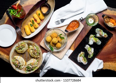 Topview Of A Table Of Fusion Food On Wood Background. Cheese Stick Fried, Spring Roll, Seafood Balls, Stuffed Pitta Bread, Cocktail 