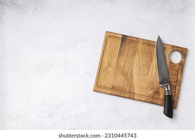 Topview of wooden chopping board and chef knife on the white table. Free space