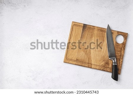 Topview of wooden chopping board and chef knife on the white table. Free space