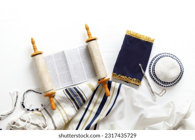 Torah scroll with a pointer, prayer shawl tallit and kippah on a light background