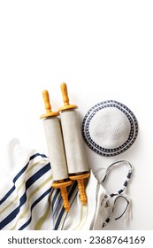 Torah scroll with a pointer, prayer shawl tallit and kippah on a light background