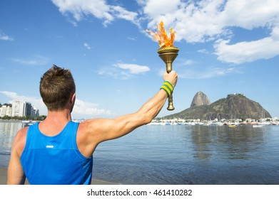 Torchbearer Athlete Holding Sport Torch Against Rio De Janeiro, Brazil Skyline With Sugarloaf Mountain Above Guanabara Bay