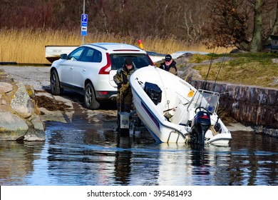 Torhamn, Sweden - March 18, 2016: The Launching Of A Small Plastic Motor Boat At A Ramp In The Marina. Two Men Push On The Boat To Help It Launch. Real People In Everyday Life.