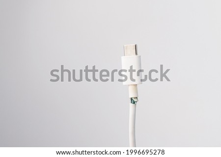 Torn cord for charging a mobile phone type si on a white background. Copy space.