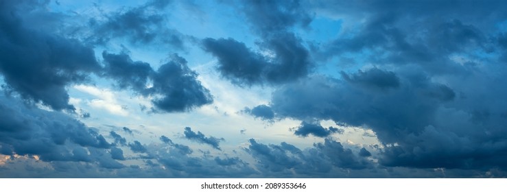 Torn formless dark clouds blown by the strong wind at evening. Scenic dramatic cloudscape at blue hour. Wide overcast sky only panorama. The weather changes from clear to stormy. Windy weather.
