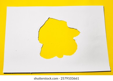 A torn hole in a white paper with a bright yellow background. Perfect for product presentations, branding, and advertising.