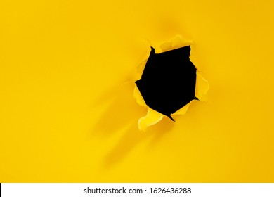 Torn Hole In Yellow Paper Background.