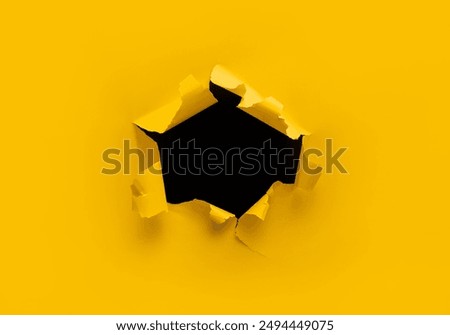 Torn hole in yellow paper with black empty background. Copy space, mockup. Place for text or logo.