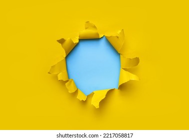 Torn Hole In Yellow Paper With Blue Empty Background. Copy Space, Mockup. Place For Text Or Logo.