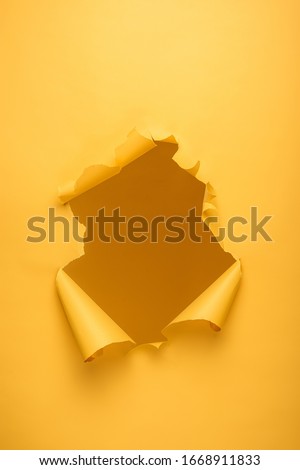 torn hole in yellow paper texture with copy space