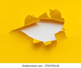 Torn hole in yellow paper with a white background. Concept for placing text or other elements, copy space.