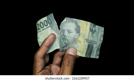 Torn money, torn 2000 rupiah banknote isolated on a black background. World economic concept.