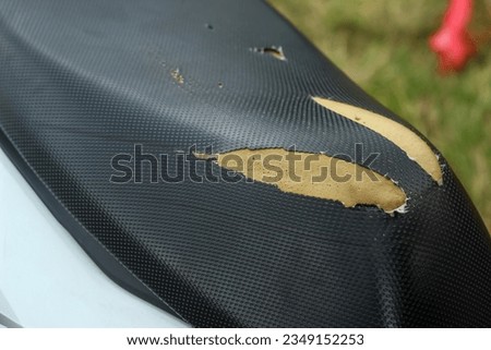 torn motorbike seats, old black leather seats with holes, damaged leather.