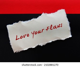 Torn note on red black background with handwritten text LOVE YOUR FLAWS, self talk to remind to learn self acceptance, embeace imperfection, learn to love yourself.