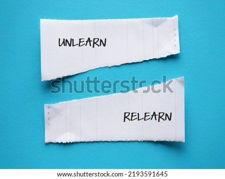 Torn note paper on blue background with handwritten text Unlearn and Relearn - knowing to discard learned outdated knowledge or skills and ready to relearn new ones