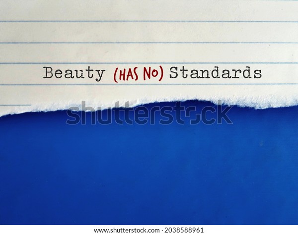 Torn note paper on blue copy space background\
with text BEAUTY HAS NO STANDARDS, concept of rebel against\
standard of beauty set by society, no more unrealistic beauty\
standard, everyone is\
beautiful