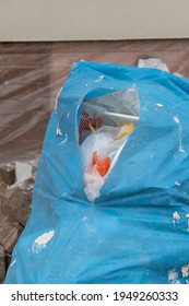 Torn Open Garbage Bag On A Construction Site 