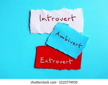 Torn paper on blue background with handwritten text - INTROVERT EXTROVERT AMBIVERT, Introvert tend to feel drained after socializing, extrovert tend to feel energized, ambivert in the middle